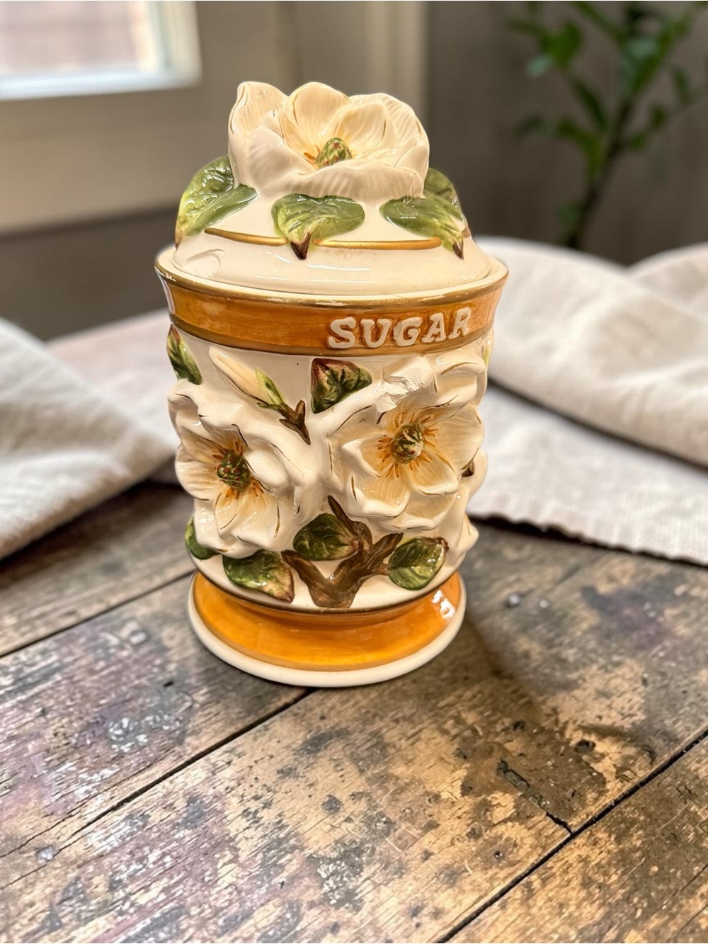 Vintage ceramic sugar canister with raised magnolia floral decoration. Has chips